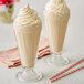 A pair of glasses of salted caramel milkshakes with straws.