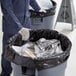 A person wearing gloves and holding a black trash bag