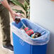 A person pouring a bottle into a Lavex trash bag in a hotel buffet.