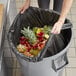 A woman holding a Lavex trash bag full of fruit.