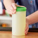 A person holding a Choice plastic container with a green lid.
