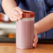 A person holding a Choice plastic container of red liquid.