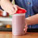 A person holding a Choice plastic container of red liquid.