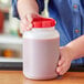 A person holding a Choice 2 Qt. jar of red liquid.