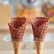 Two waffle cones with J. Hungerford Smith chocolate coating on top on a stand.