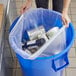 A woman holding a clear Lavex trash bag full of trash.