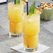 Two glasses of Ruby Kist Pineapple Juice with pineapple slices and a green leaf.