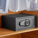 A black steel 360 Office Furniture hotel safe with electronic keypad lock on a wooden shelf.