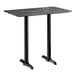 A rectangular bar height table with a smooth black finish and two sturdy black metal base plates.