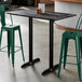 A rectangular bar height table with a smooth dark finish and two sturdy black base plates.