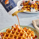 A person pouring Capora Pumpkin Pie flavoring sauce onto a waffle.
