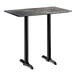 A rectangular bar height table with a smooth dark finish and two black metal end base plates.