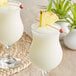 Two glasses of Coco Lopez drinks garnished with pineapple.