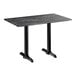 A rectangular standard height table with a smooth dark finish and two black end base plates.
