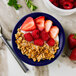 A Tuxton cobalt monkey dish filled with granola and strawberries.