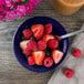 A bowl of fruit and a Tuxton cobalt monkey dish with a spoon.