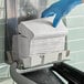 A gloved hand putting a stack of Scott Multi-fold Paper Towels into a dispenser.