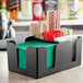 A Tablecraft black plastic bar caddy organizer with straws and napkins inside.