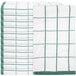 A stack of folded white and green Monarch Brands kitchen towels with green squares.