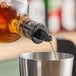 A person using a TableCraft black liquor pourer to pour alcohol into a cup.