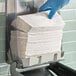 A gloved hand taking a stack of Scott C-Fold paper towels from a counter.