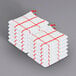 A stack of white Monarch Brands dish cloths with a red windowpane pattern and hanging loops.