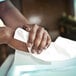 A person cleaning their hands with a white Scott Essential paper towel.