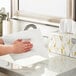 A hand using a Kleenex Professional Sheet Hand Towel to wipe a white surface.