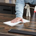 A person cleaning a table in a professional kitchen with a WypAll X70 foodservice wiper.