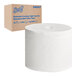 A Scott Essential box with a roll of white toilet paper next to it.