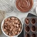 A bowl of Cacao Barry Milk Chocolate pistoles with a whisk.