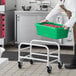 A man in a kitchen holding a Regency green meat lug rack with a green meat lug full of food.