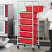 A man in a school kitchen assembling a Regency mobile lug rack with red tote boxes.