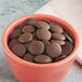 A bowl of Cacao Barry Tanzanie dark chocolate pistoles on a table.