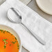 An Acopa Pangea bouillon spoon next to a bowl of broth.