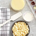 A bowl of Callebaut white chocolate chips on a table.