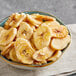 A bowl of dried banana chips on a cloth.