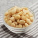 A bowl of raw macadamia nuts on a tablecloth.