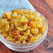 A bowl of golden raisins on a wood surface.