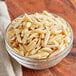 A bowl of blanched slivered almonds on a wooden table.