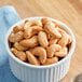 A bowl of roasted salted cashews on a table with a blue cloth.