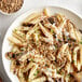 A white plate of pasta with mushrooms and Roasted Salted Sunflower Seeds.