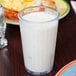 A close up of a GET Clear SAN Plastic tumbler filled with milk on a table.