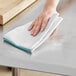 A hand wiping a counter with a green-striped herringbone kitchen towel.