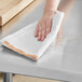 A hand wiping a counter with a white Choice herringbone kitchen towel.