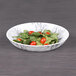 A black marble embossed melamine bowl filled with salad and tomatoes.