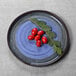 An Elite Global Solutions Monet cobalt melamine plate with red tomatoes and leaves on it.