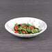 An Elite Global Solutions black marble embossed melamine bowl filled with salad with tomatoes and greens.