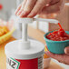 A person using a Choice condiment pump to pour ketchup into a bowl.