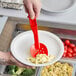 A person using a red Cambro Camwear perforated spoon at a salad bar.